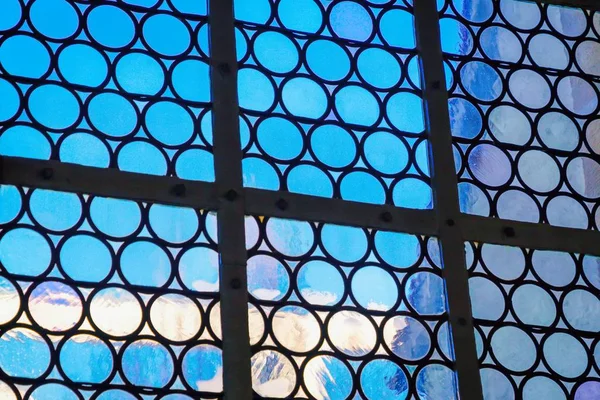 Beautiful window with forged circles and blue sky. Detail