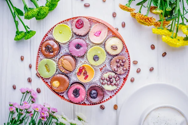 Dulces de chocolate de lujo en una caja de regalo y crisantemos de colores sobre fondo blanco. Vista superior — Foto de Stock