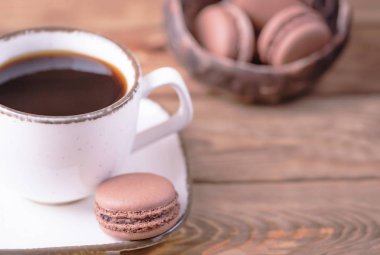 Beyaz siyah kahve ve tatlı çikolata macaroons ahşap arka plan üzerinde Fransız. Kopya alanı
