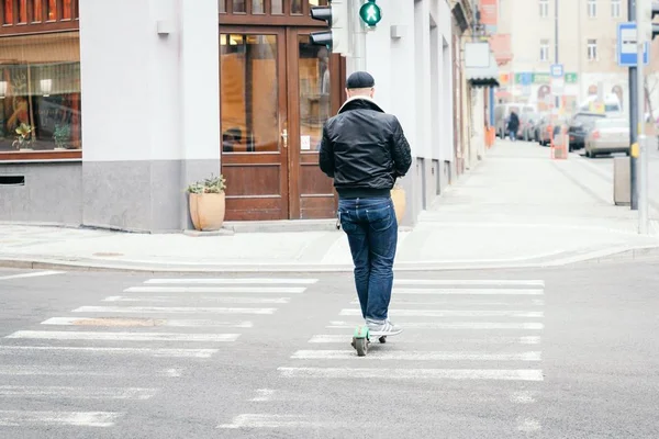 Snygg ung man rider en kick scooter på övergångsstället — Stockfoto