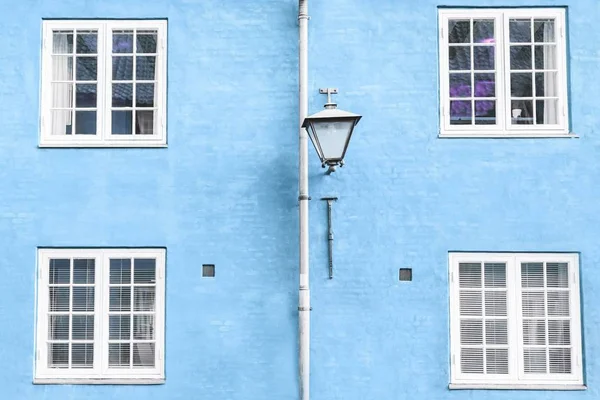 Pared azul claro, farol de calle y cuatro ventanas blancas — Foto de Stock