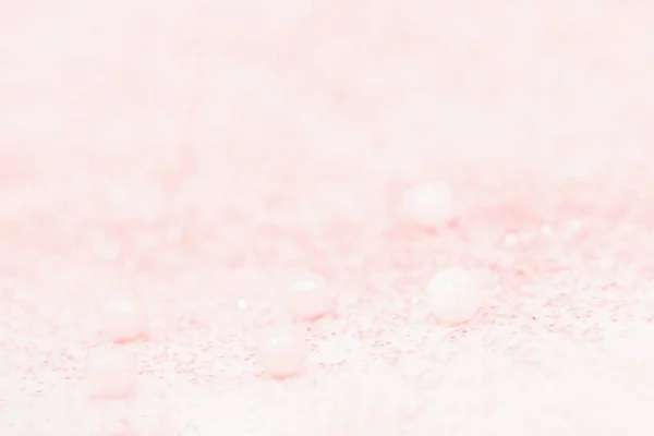 Delicate light coral color background. Sugar balls and sparkles.