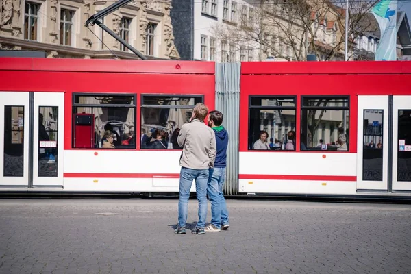 Erfurt, Niemcy. 7 2019 kwietnia. Dwa dorywczo młodych mężczyzn w centrum miasta na czerwonym tle tramwaju — Zdjęcie stockowe