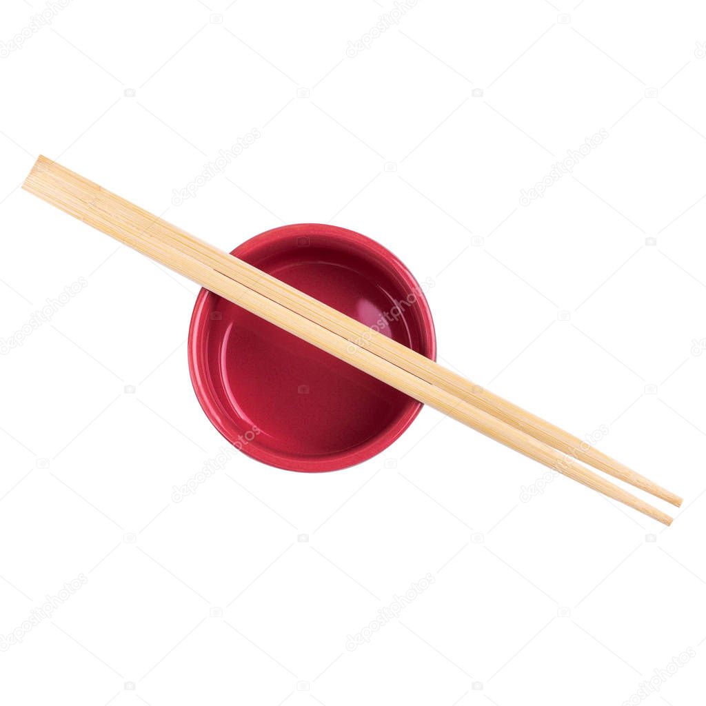 Japanese sushi sticks or chopsticks over red sauce bowl isolated on white background. Top view