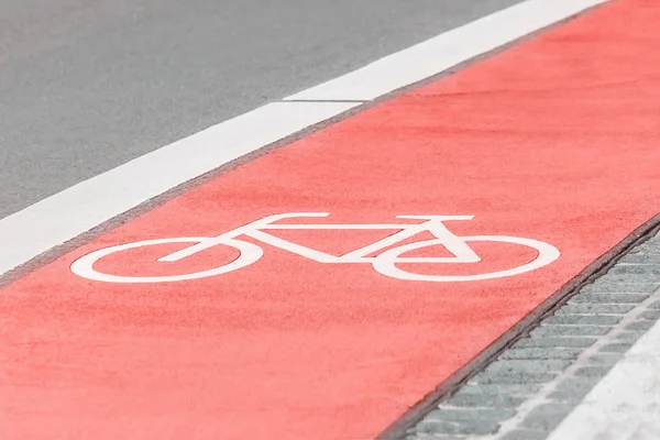 Piste cyclable avec un symbole de vélo sur la route asphaltée. Couleur corail rose . — Photo