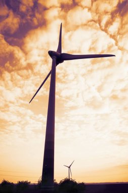 Akşam gökyüzü arka planında rüzgar türbini. Yel değirmenleri ve güzel gün batımı