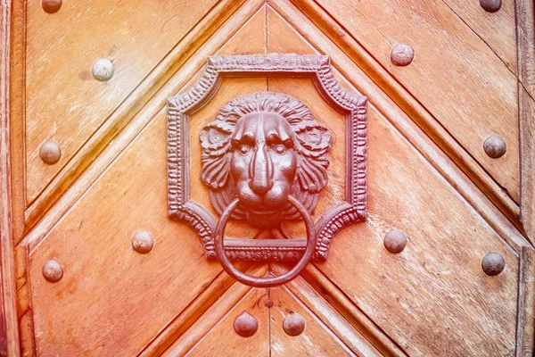 Una antigua puerta de madera con puerta golpeadora en forma de león. Naranja tonificado — Foto de Stock