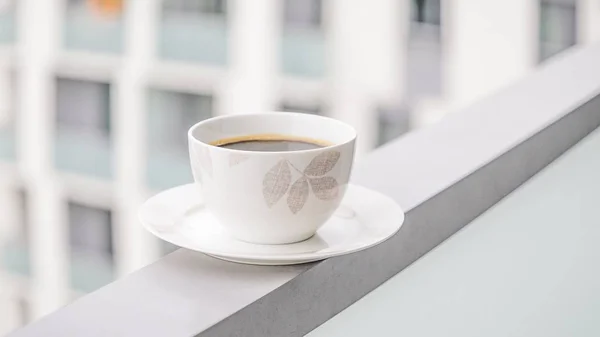 Porcelanowa filiżanka czarnej kawy na tle okna. Kawa w wielkim mieście. 16:9 Panoramiczny format. Kopiuj przestrzeń — Zdjęcie stockowe