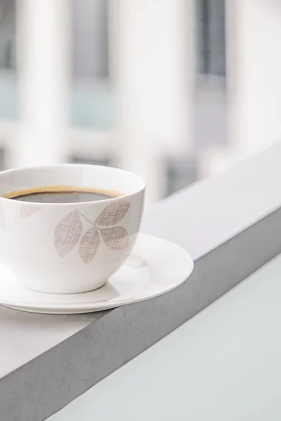 Taza de porcelana de café negro sobre un fondo de ventanas. Copiar espacio — Foto de Stock