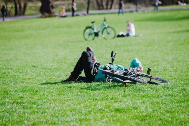 Parkta yeşil çimenlerin üzerinde bisikletli bir adam.