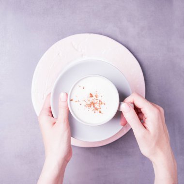 Kahve kapuçino fincanlı kadın elleri. Çıplak oje ile Manikür. Gri arka plan, kopyalama alanı, üst görünüm