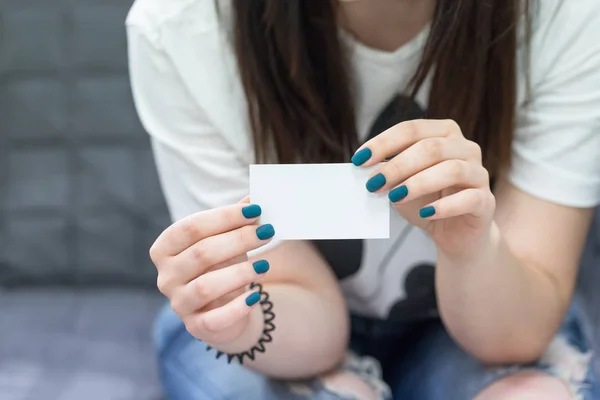 Manos femeninas sosteniendo la tarjeta de visita vacía blanca. Manicura con esmalte de uñas azul turquesa profundo — Foto de Stock