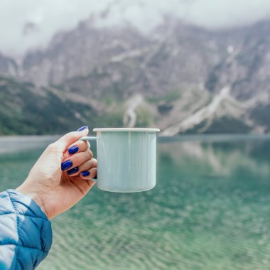 Nane rengi mine fincan tutan kadın el. Kristal berraklığında göl ve dağlar. Tatra Ulusal Parkı, Polonya. Ünlü morskie Oko gölü veya Deniz Gözü