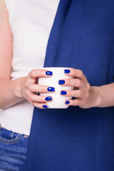 Vackra kvinnliga händer som håller vit kopp. Manikyr med blått nagellack — Stockfoto