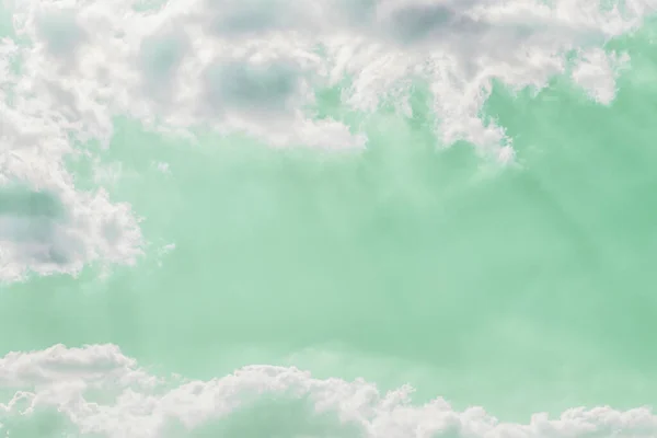 淡淡的光芒穿过云彩，映衬着淡绿色的天空背景 — 图库照片