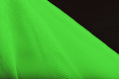 Siyah arkaplanda yumuşak kıvrımlı yeşil ipek, kopyalama alanı