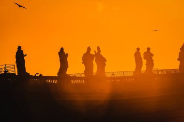 Vatikan 'da azizlerin heykelleri. Turuncu arka planda siluet