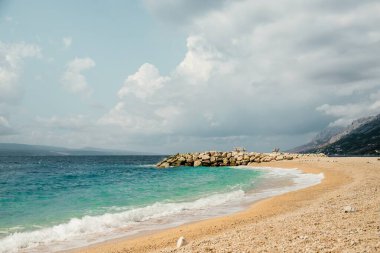 Zümrüt suyu ve gri bulutları olan güzel bir deniz manzarası. Brela Hırvatistan, Makarska Riviera