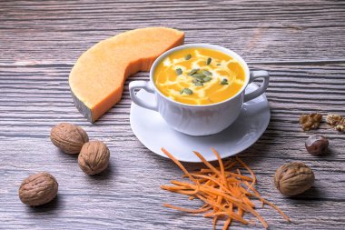 Kabak kremalı çorba. Köy ahşap masa üzerinde tohumlar ve cevizlerle servis edilir. Geleneksel sonbahar yemeği ve sağlıklı mevsimsel konfor yemekleri.