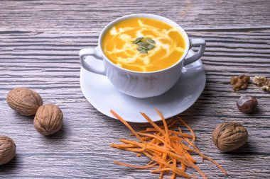 Kabak kremalı çorba. Köy ahşap masa üzerinde tohumlar ve cevizlerle servis edilir. Geleneksel sonbahar yemeği ve sağlıklı mevsimsel konfor yemekleri.