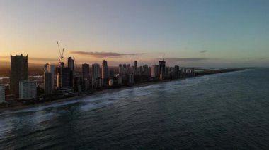 Günbatımında Avustralya, Queensland 'daki Gold Coast' un muhteşem 4K hava aracı görüntüleri. Video gösterimlerinde Sörfçüler Cenneti gökdelenler altın akşam ışığı, kumlu plajlar ve Pasifik boyunca dalgalanan okyanus dalgalarıyla gökdelenler yükseliyor.