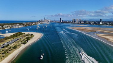 Altın Sahil, Queensland, Avustralya 'nın bu insansız hava aracı görüntüsü çarpıcı şehir silueti, yüksek kuleler, altın plajlar ve ikonik Sörfçüler Cenneti' ni içeriyor. Fotoğraf, deniz kenarındaki ışıl ışıl kanalları, lüks marinaları ve yol alan tekneleri yakalıyor.