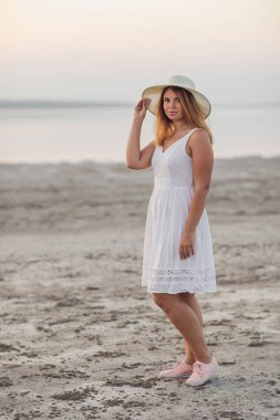 Genç bir kadın sahilde yürüyor.