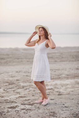 Genç bir kadın sahilde yürüyor.