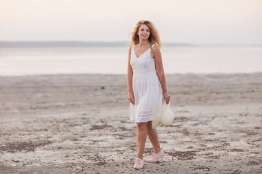 Genç bir kadın sahilde yürüyor.