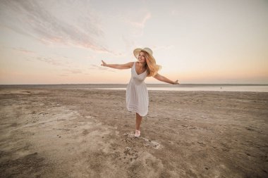 Genç bir kadın sahilde yürüyor.