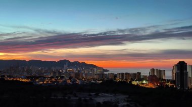 Nefes kesici ve çarpıcı bir günbatımı manzarasının tadını çıkarın. Şehir ve dağları güzel aydınlatan huzurlu sahil manzarası.