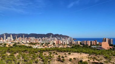 Arka planda dağlar ve canlı şehir mimarisi olan kıyı şehrinin nefes kesici manzarası..