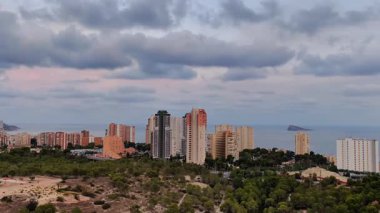 Gökyüzündeki resimsel bulutlar tarafından güzel çerçevelenmiş kentsel binaların olduğu çarpıcı bir kıyı manzarası deneyin.