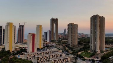 Nefes kesici, çarpıcı bir hava manzarası modern gökdelenleri sergiliyor. Akşam gökyüzüne karşı parlak bir şekilde aydınlatılıyor.