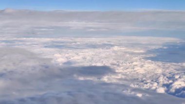 Göz kamaştırıcı bir hava manzarası üzerinde açık mavi gökyüzünde yüzen tüylü beyaz bulutları güzel bir şekilde yakalıyor.