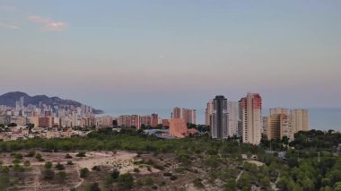 Gün batımında, modern mimari ve dingin doğanın sergilendiği kıyı kentinin çarpıcı manzarası..