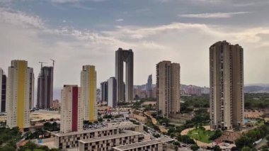 Güzel bir hava manzarası, canlı, modern bir şehir manzarası, yüksek binalar ve geniş yeşil alanlarla dolu.