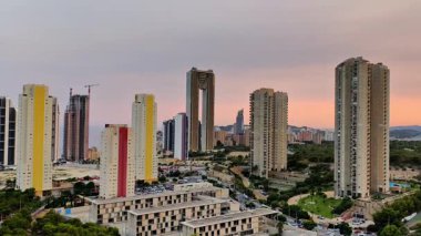 Nefes kesici bir şehir silueti, çarpıcı bir günbatımında canlı cephelere sahip modern binalar.