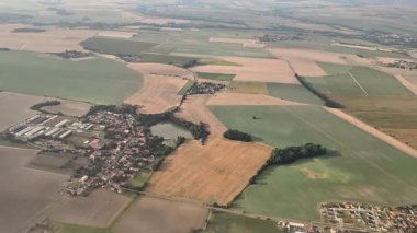 Çarpıcı bir hava görüntüsü, pitoresk bir kırsal bölgedeki tuhaf bir köyün yanındaki canlı tarlaları gösteriyor.