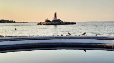 Deniz kenarındaki büyüleyici bir deniz feneri kıyı manzarasının sakin ve sakin atmosferini arttırır.