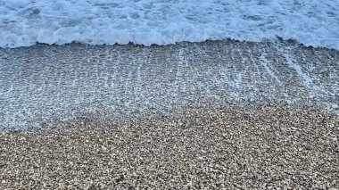 Huzurlu bir an. Dalgalar bir çakıl taşı plajını nazikçe yıkıyor. Şaşılacak güzellikte ve çekicilikte sergiliyor.