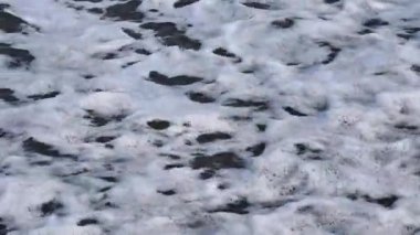 İşte köpüklü okyanus dalgalarının büyüleyici ve büyüleyici görüntüsü el değmemiş kumsalda yavaşça akıyor.