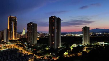 Alacakaranlıkta canlı şehir ışıklarının binaları aydınlattığı şehir siluetinin nefes kesici manzarası..