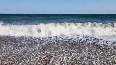 Sakin bir sahil manzarası hayal edin. Yumuşak dalgalar zarif bir şekilde altın kıyıya çarpıyor. Açık mavi gökyüzünün altında.