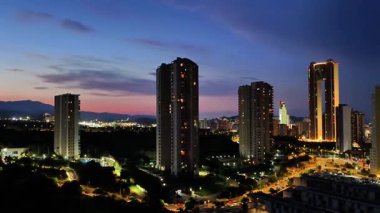 Günbatımında aydınlanan modern şehrin nefes kesici manzarası, yüksek binalar ve canlı renkler sergiliyor..