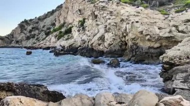 Nefes kesen manzara, canlı, çarpan dalgalarla süslenmiş kayalık bir kıyı şeridini ve berrak mavi suyu gözler önüne seriyor.