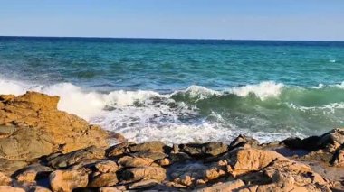 Experience the soothing rhythm of ocean waves crashing against rugged rocks in a peaceful coastal scene