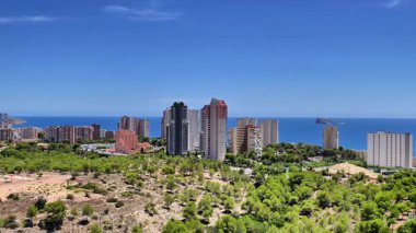 Deniz kenarında canlı bir şehir, yemyeşil ve açık mavi gökyüzüyle çevrili güzel bir manzara..