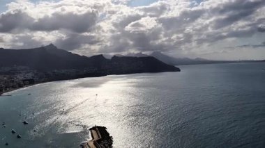 Breathtaking aerial perspective of a tranquil coastline showcasing majestic mountains alongside a shimmering sea