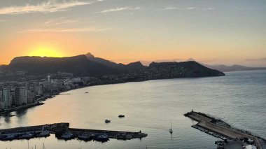 Gün batımının nefes kesen manzarası kıyı manzarasını ve akşam ışığında sakin sularını aydınlatıyor.